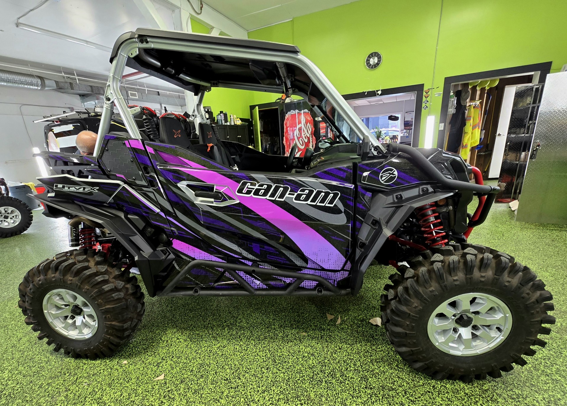 A Can-Am Maverick Sport side-by-side with a black, khaos purple, asphalt gray, lilac purple, and gang purple Electra custom vinyl wrap with silver flake laminate.